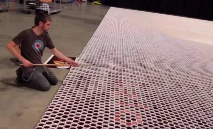 Il aligne un par un plus de 66000 gobelets remplis d’eau. Lorsque la caméra dézoome, VOICI ce qui apparaît. Bluffant !